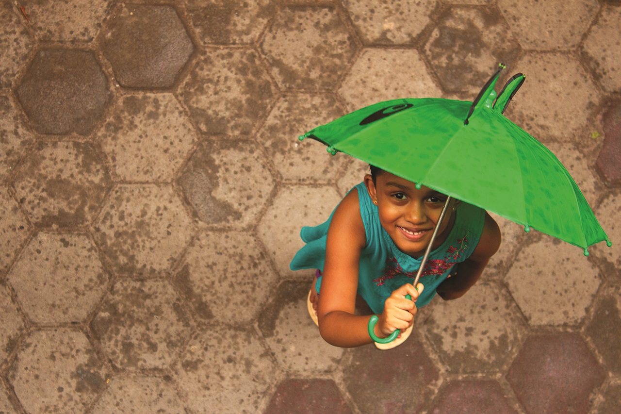 Smiley girl with umbrella on a monsoon day